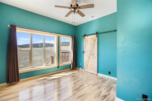 spare room with hardwood / wood-style floors, ceiling fan, and a barn door