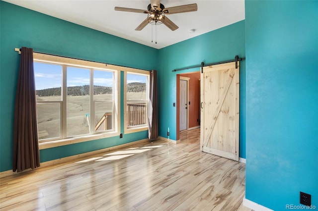 spare room featuring hardwood / wood-style floors, ceiling fan, and a barn door