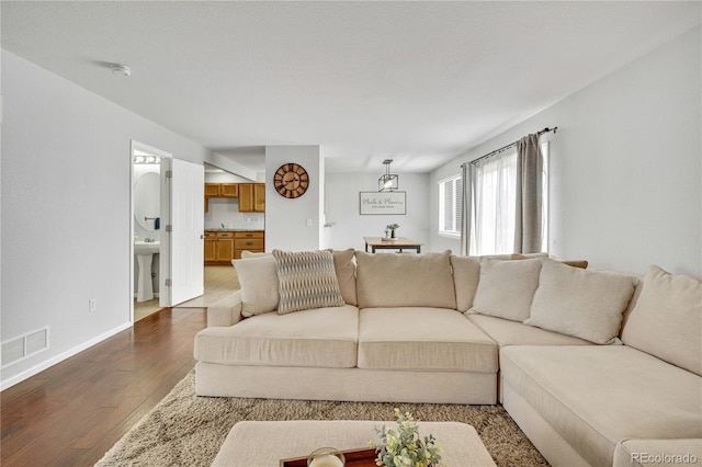 living area featuring baseboards, visible vents, and dark wood finished floors