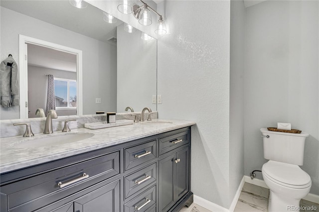 full bath with toilet, marble finish floor, baseboards, and a sink