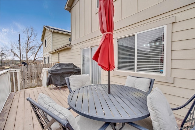 deck featuring outdoor dining space, grilling area, and fence