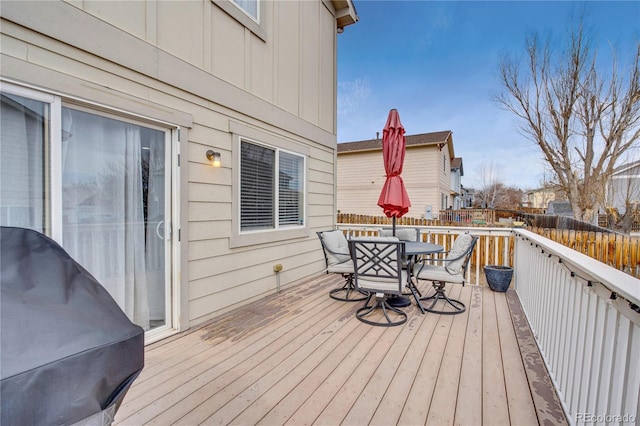 deck with outdoor dining space, a grill, and fence