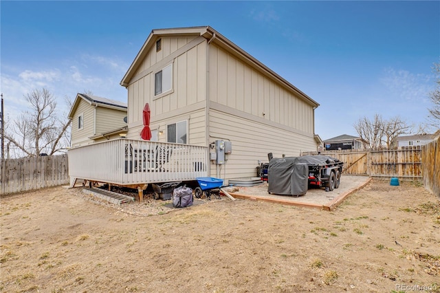 back of property with a fenced backyard, a deck, and board and batten siding