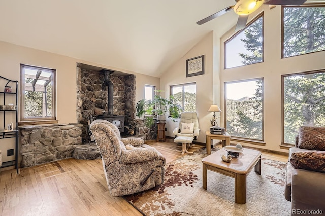 interior space featuring high vaulted ceiling, a wood stove, plenty of natural light, and wood finished floors