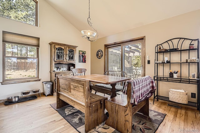dining room with light wood-type flooring, high vaulted ceiling, and visible vents