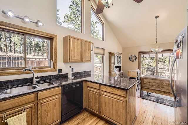 kitchen with black dishwasher, a sink, a peninsula, stainless steel refrigerator, and high vaulted ceiling