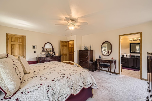 bedroom featuring ensuite bathroom, baseboards, a ceiling fan, and light carpet