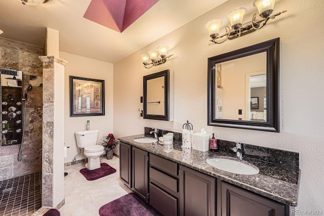 bathroom with double vanity, a tile shower, a sink, and toilet