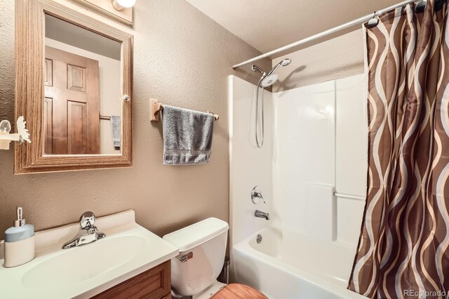 bathroom with toilet, vanity, a textured wall, and shower / tub combo with curtain
