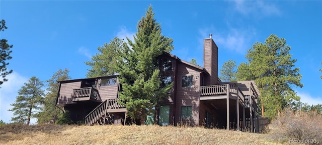 back of house featuring stairway, a deck, and a chimney