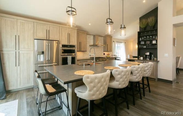 9768 Otis Dr, Westminster, CO 80021 - kitchen with dark countertops, appliances with stainless steel finishes, wood finished floors, a sink, and wall chimney exhaust hood