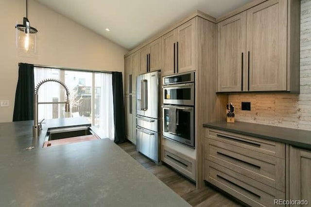 9768 Otis Dr, Westminster, CO 80021 - kitchen featuring appliances with stainless steel finishes, dark countertops, vaulted ceiling, wood finished floors, and a sink