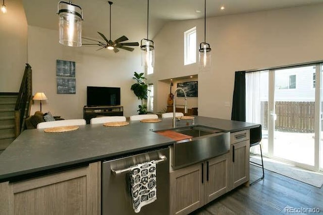 9768 Otis Dr, Westminster, CO 80021 - kitchen featuring ceiling fan, stainless steel dishwasher, a center island with sink, a sink, and dark wood-type flooring