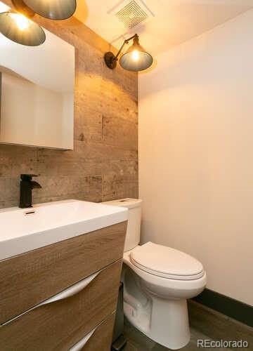 9768 Otis Dr, Westminster, CO 80021 - bathroom featuring vanity, toilet, tile walls, and visible vents