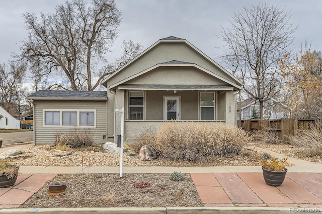 bungalow-style home featuring a shingled roof, fence, and stucco siding