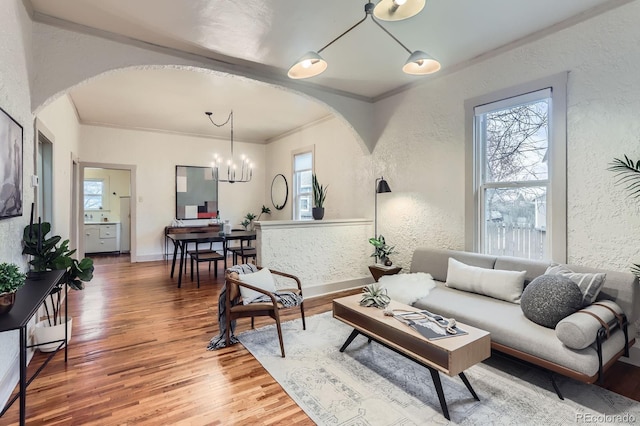 living room featuring a wealth of natural light, arched walkways, wood finished floors, and a textured wall