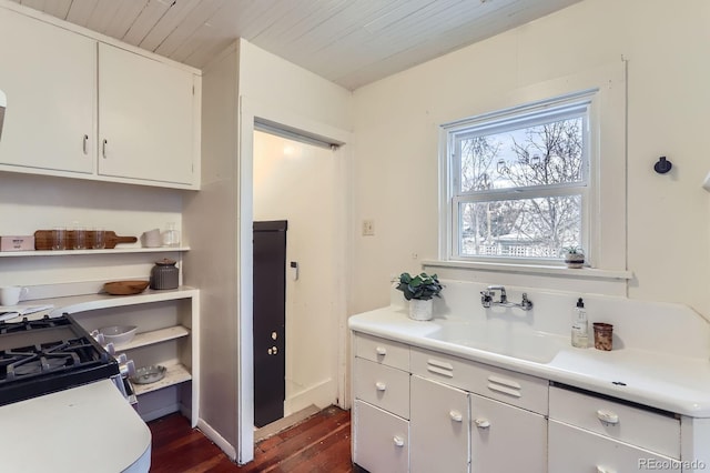 kitchen featuring white cabinets, dark wood finished floors, wooden ceiling, light countertops, and a sink