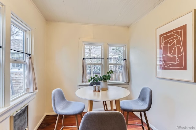 dining space with baseboards, ornamental molding, wood finished floors, and a healthy amount of sunlight