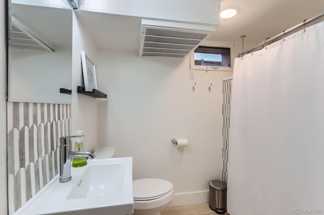 bathroom featuring toilet, baseboards, and a sink