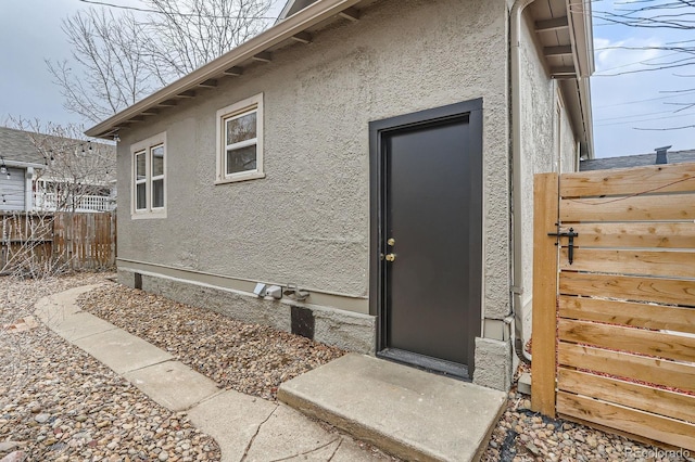 property entrance with fence and stucco siding