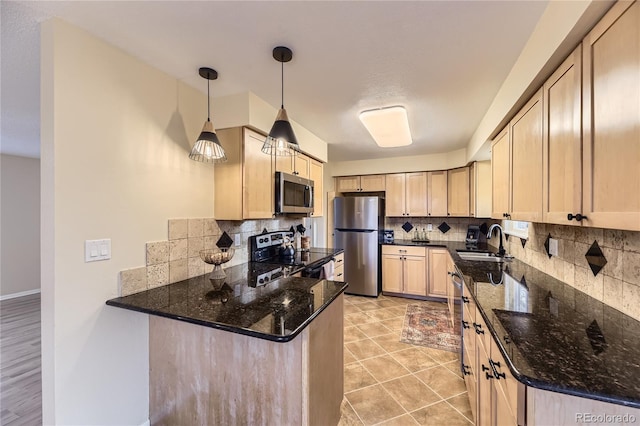 kitchen with backsplash, dark stone countertops, sink, and stainless steel appliances