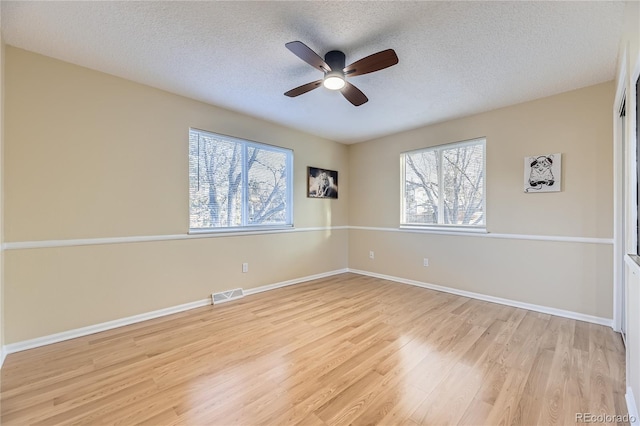 empty room with ceiling fan, light hardwood / wood-style floors, and a textured ceiling