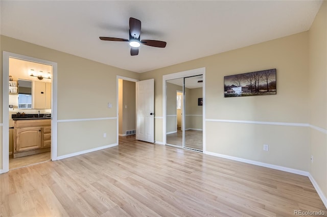 unfurnished bedroom with sink, ensuite bath, ceiling fan, light hardwood / wood-style floors, and a closet