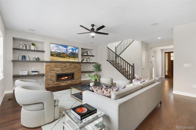 living room featuring built in shelves, ceiling fan, a fireplace, and dark hardwood / wood-style floors