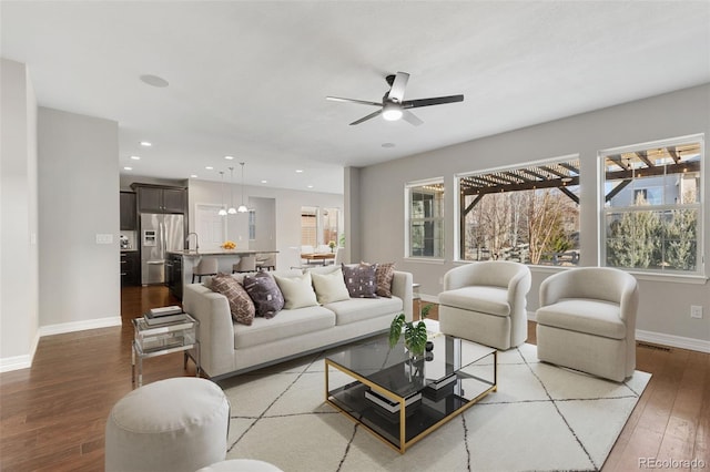 living room featuring sink, wood-type flooring, and ceiling fan