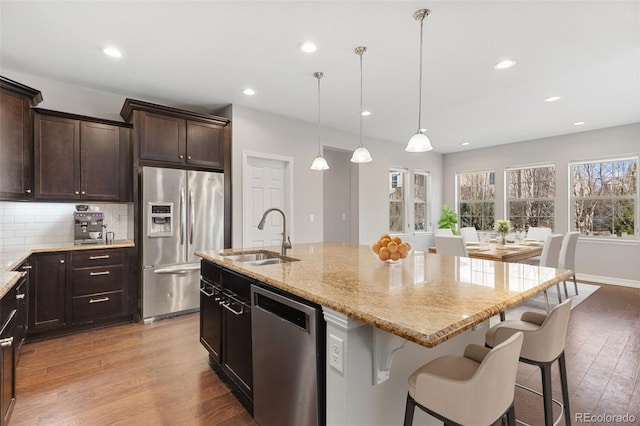 kitchen with pendant lighting, a kitchen island with sink, a breakfast bar area, appliances with stainless steel finishes, and sink