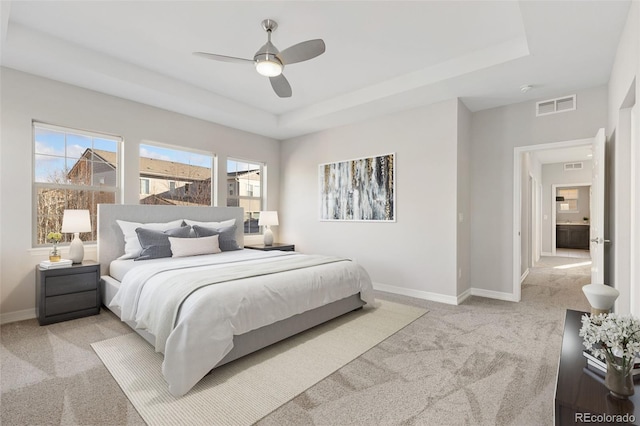 bedroom with a raised ceiling, ceiling fan, and light colored carpet