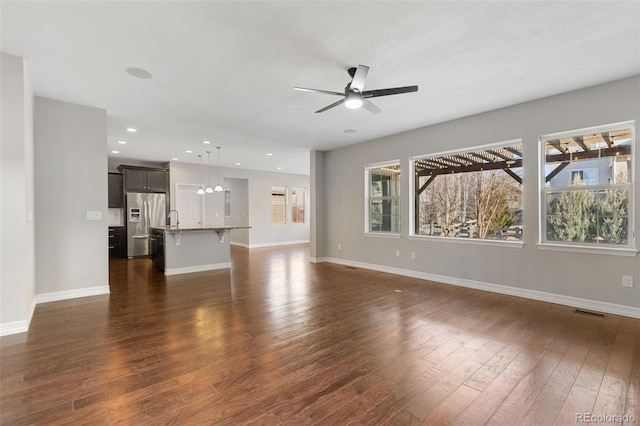 unfurnished living room with ceiling fan, dark wood-type flooring, and sink