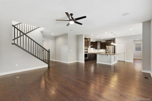 unfurnished living room featuring ceiling fan and dark hardwood / wood-style flooring