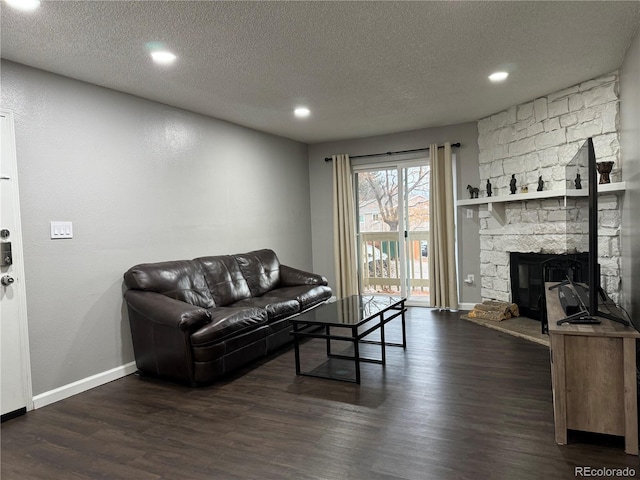 living room featuring a fireplace, a textured ceiling, and dark wood-type flooring