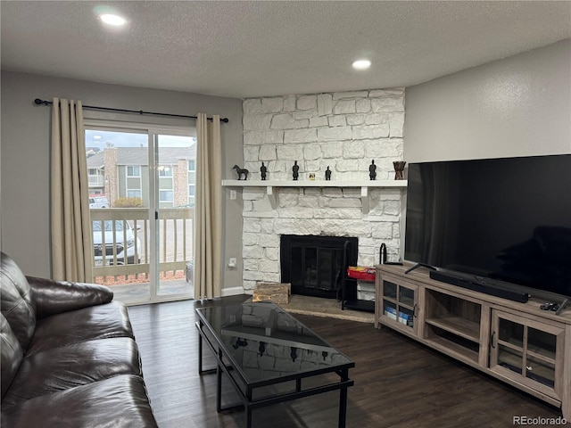 living room with a fireplace, a textured ceiling, and dark wood-type flooring