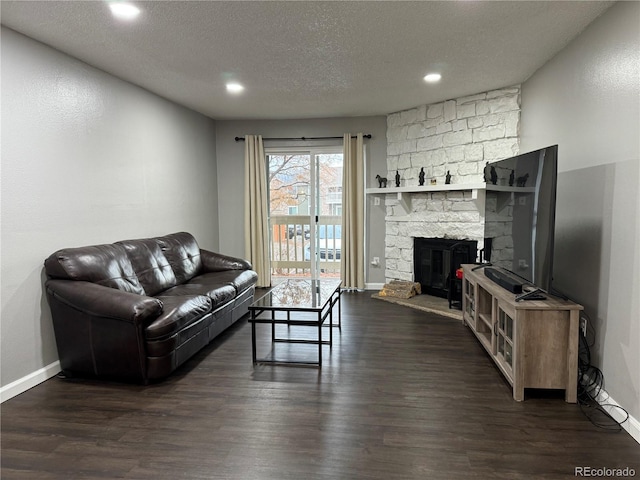 living room featuring a textured ceiling, a fireplace, and dark hardwood / wood-style floors