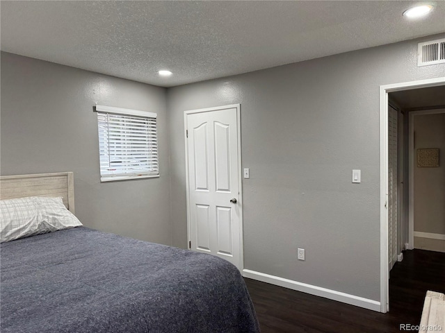 bedroom with dark hardwood / wood-style flooring and a textured ceiling