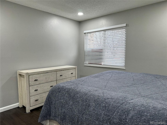 bedroom featuring dark hardwood / wood-style floors and a textured ceiling