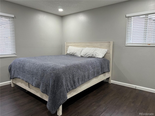 bedroom with a textured ceiling and dark wood-type flooring