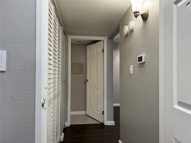 hallway with a textured ceiling and dark hardwood / wood-style floors