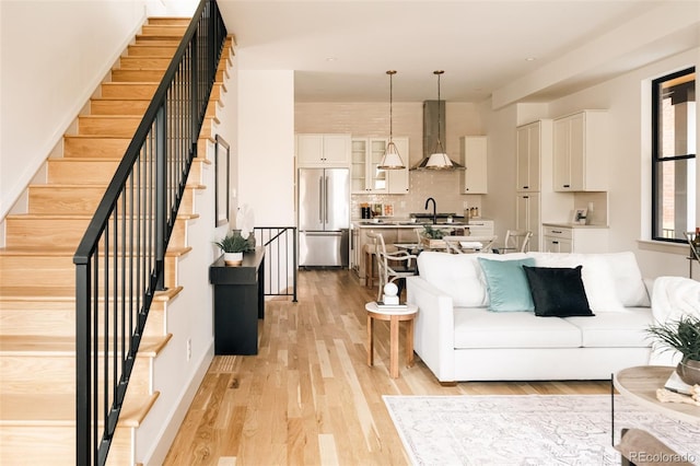 living area with light wood finished floors and stairway