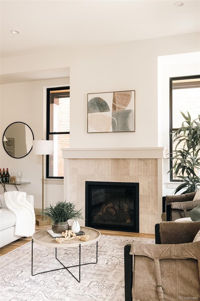 living area with recessed lighting, a glass covered fireplace, and wood finished floors