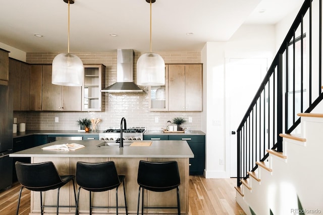 kitchen featuring a breakfast bar, light countertops, wall chimney range hood, and light wood-type flooring