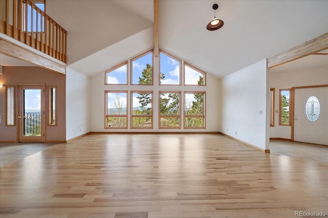 23007 Big Game Trl, Conifer, CO 80433 - unfurnished living room with beamed ceiling, wood finished floors, baseboards, and high vaulted ceiling