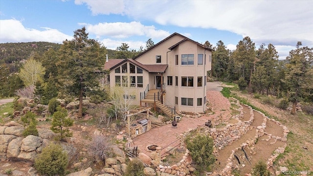 23007 Big Game Trl, Conifer, CO 80433 - rear view of house with stucco siding, stairs, and a patio area