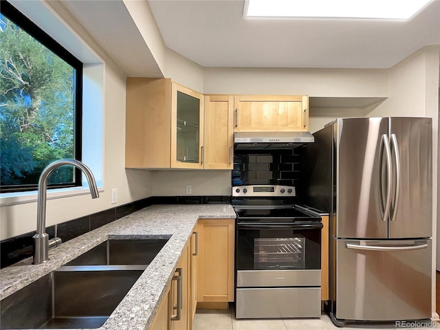 kitchen featuring appliances with stainless steel finishes, light brown cabinetry, light stone counters, sink, and light tile patterned floors