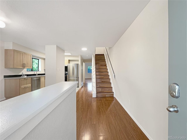 kitchen featuring hardwood / wood-style flooring, sink, stainless steel appliances, and light brown cabinetry