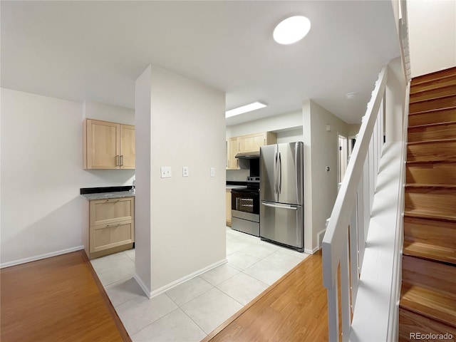 kitchen with light brown cabinetry, light tile patterned floors, and appliances with stainless steel finishes