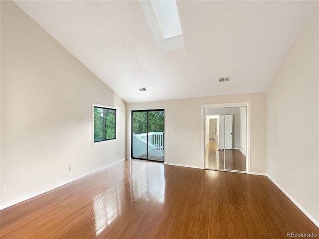 spare room featuring hardwood / wood-style flooring and vaulted ceiling with skylight