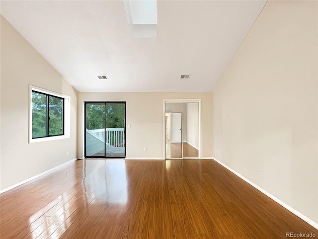 empty room with hardwood / wood-style floors and vaulted ceiling